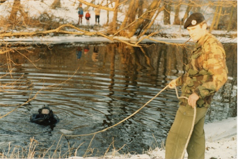 A soldier assisting a diver during a river search